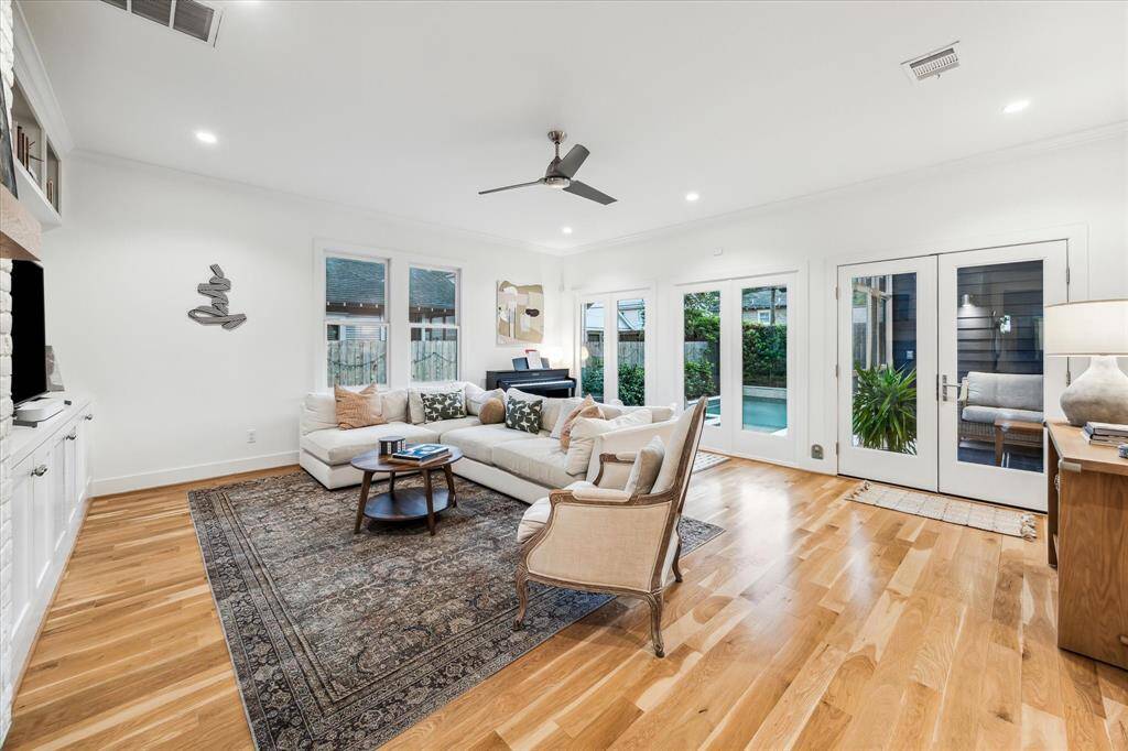 The spacious family room features white oak floors and a wall of windows overlooking the gorgeous backyard. The French doors lead to the screened in porch.