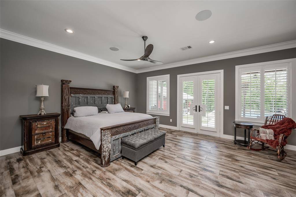 The impressive primary suite features custom shutters and French doors, providing direct access to the backyard patio and pool.
