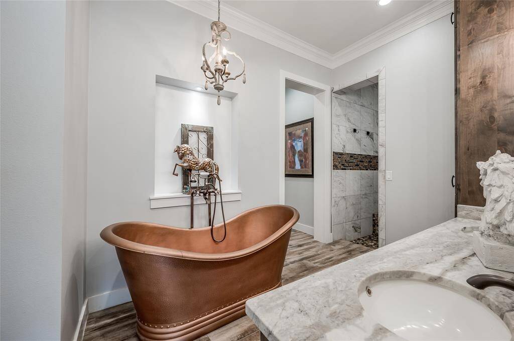 Large copper soaking tub with chandelier and oversized walk-in shower.