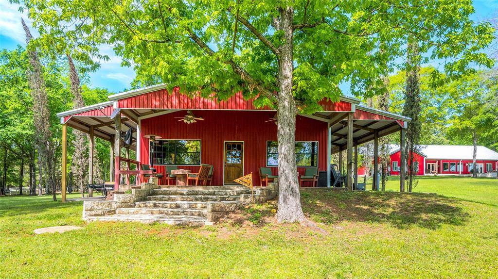 The guesthouse has a large covered patio, lean-to, and oversized steps leading to the backyard.