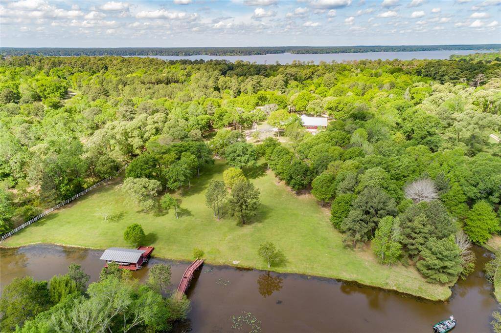 Aerial view of the back portion of the property, lake, private dock, and walking bridge.