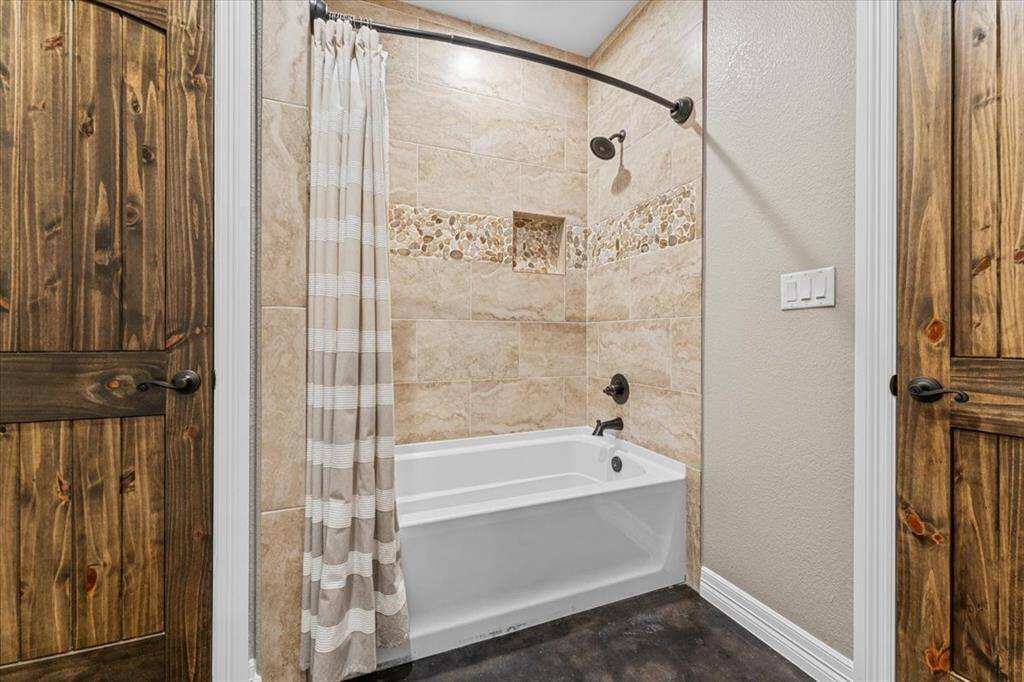 The shared tub/shower combo area with tile to the ceiling, with oil rubbed bronze finishes and again durable stained concrete flooring.