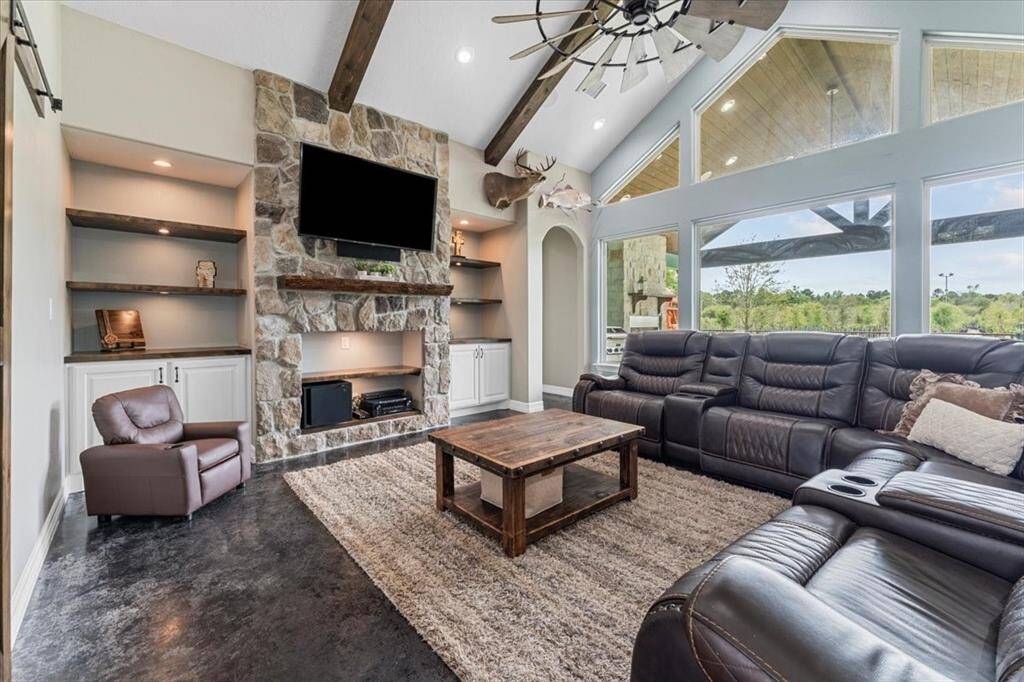 Wow, the living room has vaulted ceilings with exposed beams, with built-ins shelves for your family photos and cabinets for boardgames, along with large windows looking onto the patio.