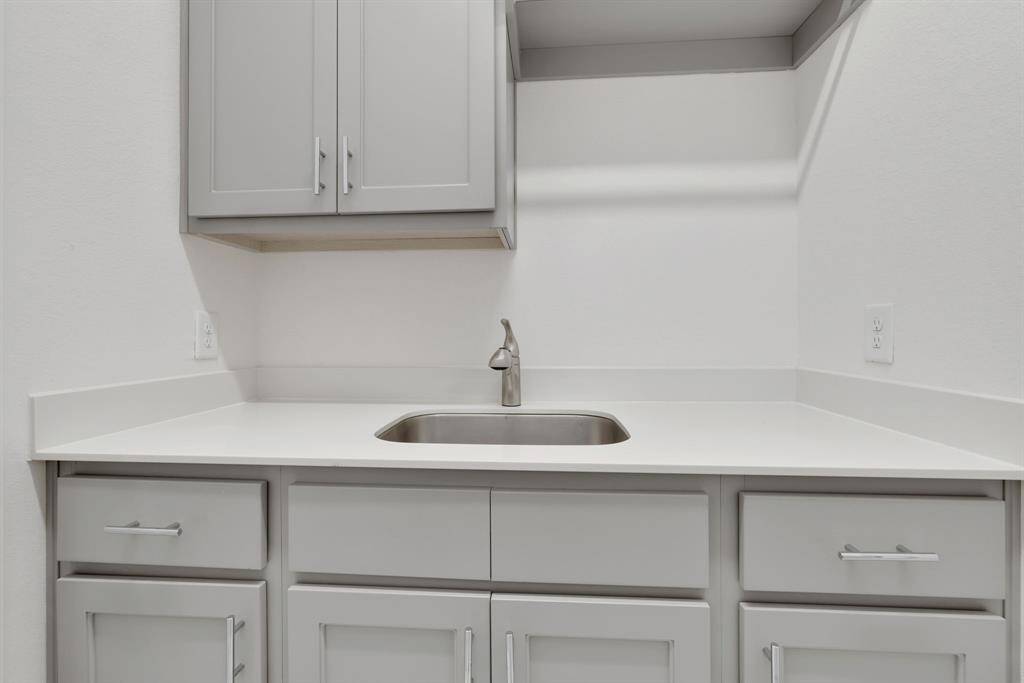 The laundry room with built in cabinetry and a full size sink.