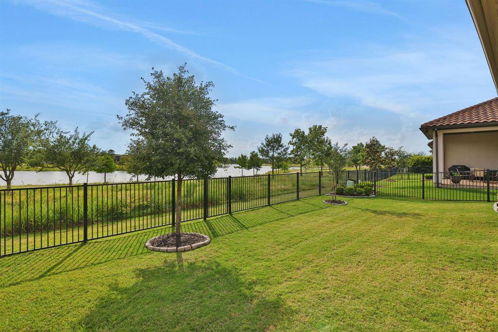 The backyard with a wrought iron fence and gate for access to the greenbelt and lake views.