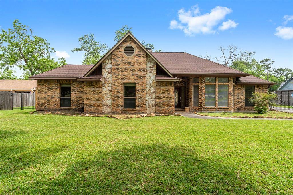 This charming brick home features a classic design with a gable roof and large windows. It sits on a spacious, well-maintained lawn, offering ample outdoor space. The mix of brick and stone accents adds character to the exterior.