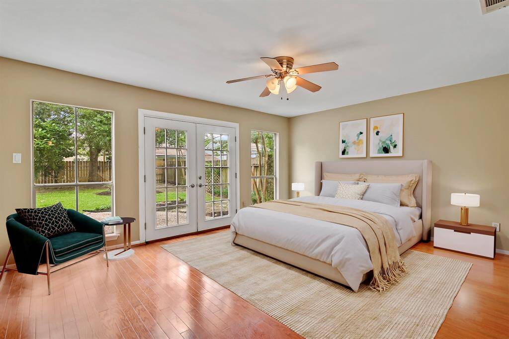 The primary bedroom is made for relaxation with wood floors, wall of windows and double doors leading to the backyard. *Virtually staged photo*