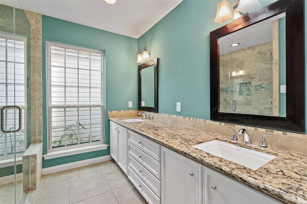 Primary bathroom features double rectangle under-mount sinks, granite counter tops and plenty of cabinets and drawers for storage.