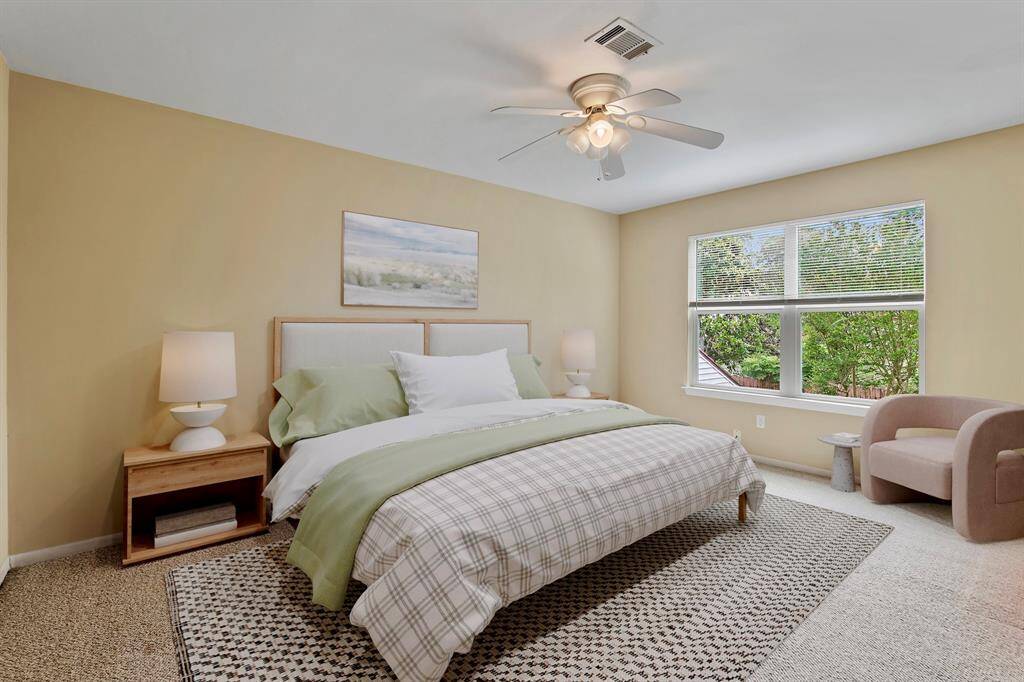 Upstairs secondary bedroom features carpet, ceiling fan and large picture window. *Virtually staged photo*