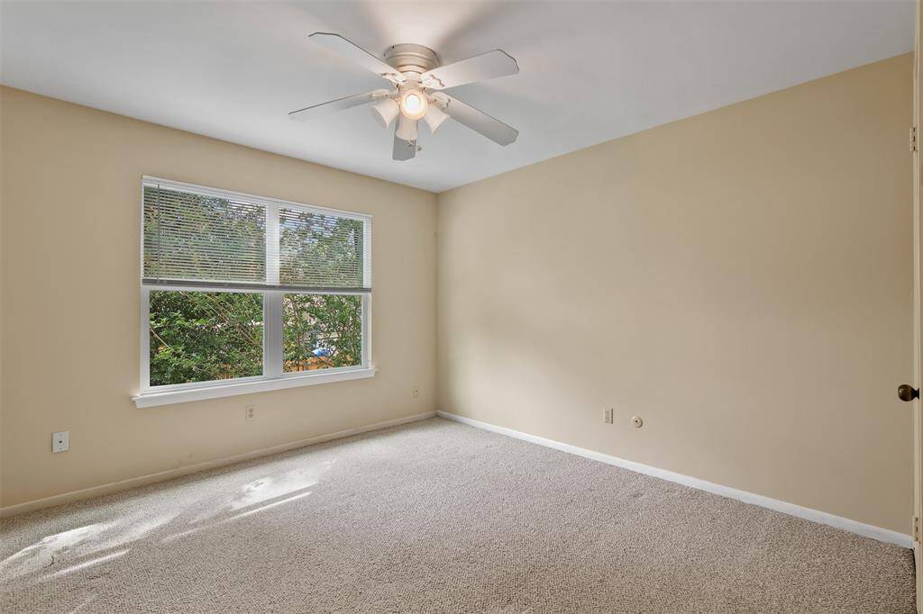 Second additional bedroom upstairs features carpet, ceiling fan and picture window.