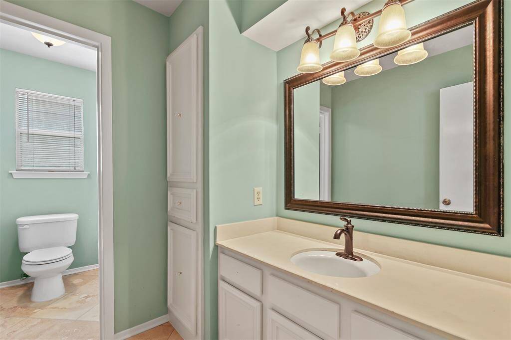 Secondary full bathroom upstairs has single sink vanity with framed mirror and lots of cabinet and storage space.