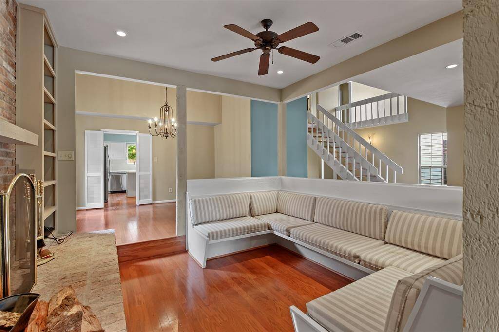 Another view of the formal living room with wood floors, ceiling fan, canned lighting and step down entry.