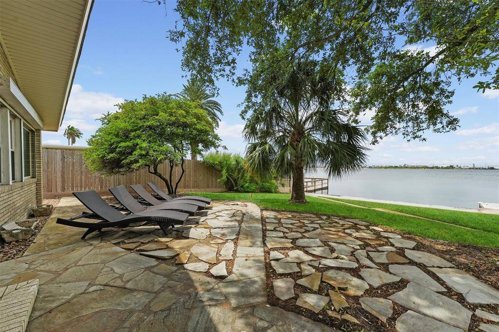 Relax on the stone patio nestled under palm trees, offering the perfect spot for sunbathing and unwinding.