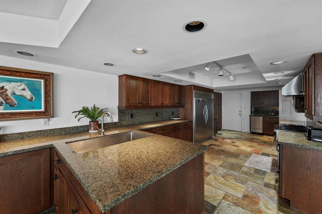 Cook in style with this spacious galley kitchen—dual sinks, sleek stainless steel appliances, granite counters, and plenty of storage.