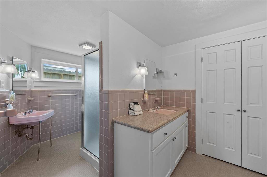 The downstairs primary bathroom offers a coastal vintage charm with double sinks and a stand up shower.
