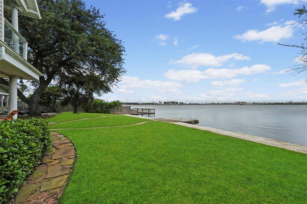 Lush green backyard running along the water’s edge with mature trees.