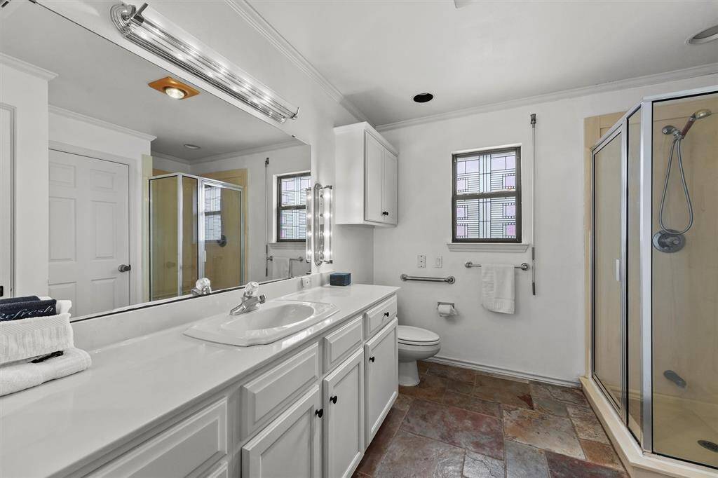 This clean and spacious bathroom features a glass-enclosed shower, vanity, and bright lighting.