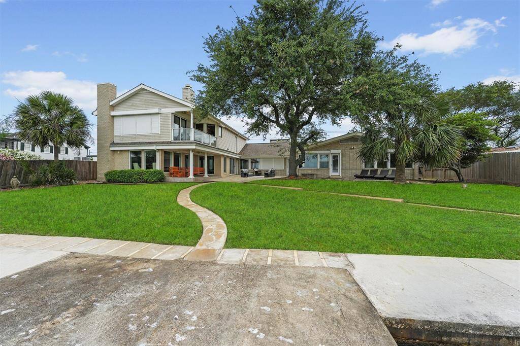 A full view of the home from the yard, showcasing the patios and upper balcony—perfect for enjoying both outdoor living and stunning views.