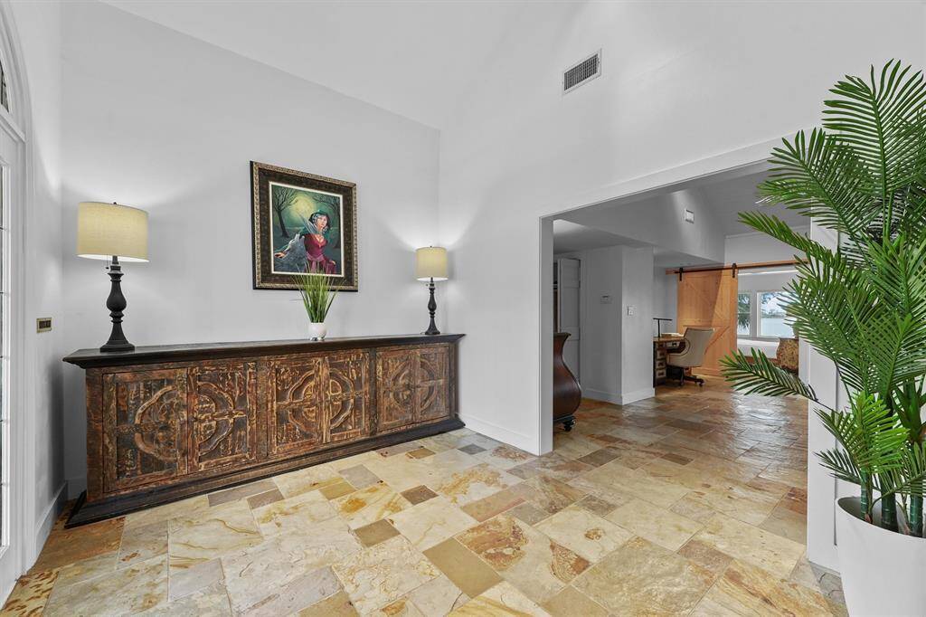 Step into style—natural stone floors, elegant details, and a peek into the home office just ahead.