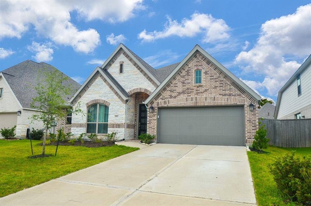Charming single-story home with a brick and stone exterior, featuring a gabled roof and a spacious two-car garage. The well-maintained lawn and driveway provide excellent curb appeal in a quiet neighborhood setting.