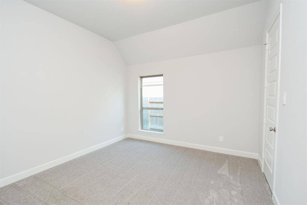 This room features neutral walls, plush carpeting, and a large window that lets in plenty of natural light, creating a bright and inviting space.