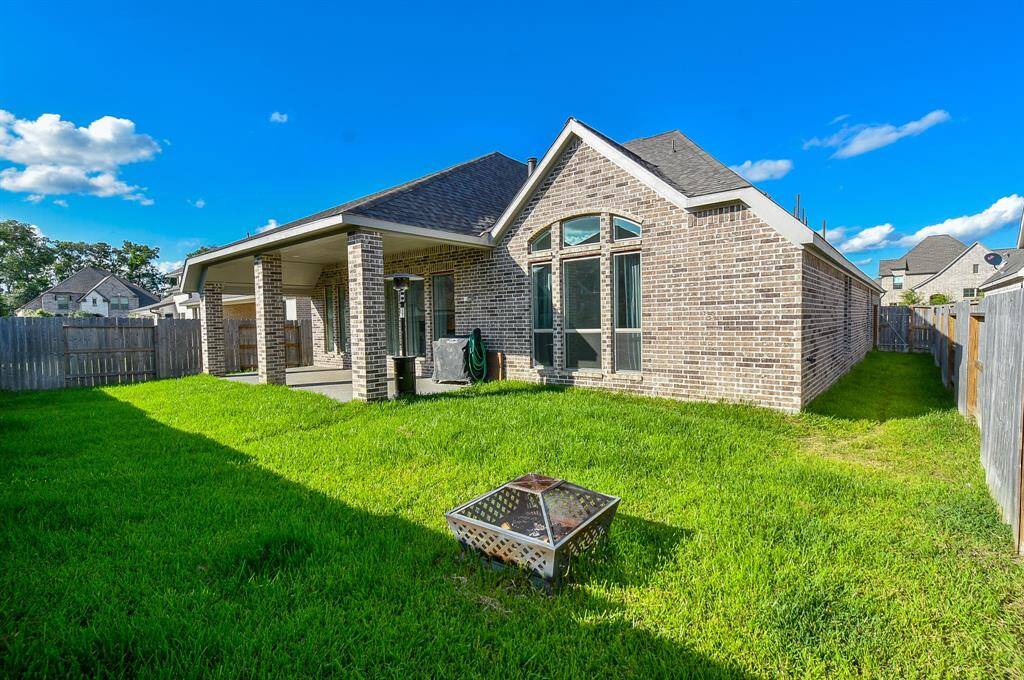 This photo showcases a charming brick home with a spacious, well-maintained backyard. The covered patio offers a perfect space for outdoor relaxation or entertaining. The yard is enclosed by a wooden fence, providing privacy and security.