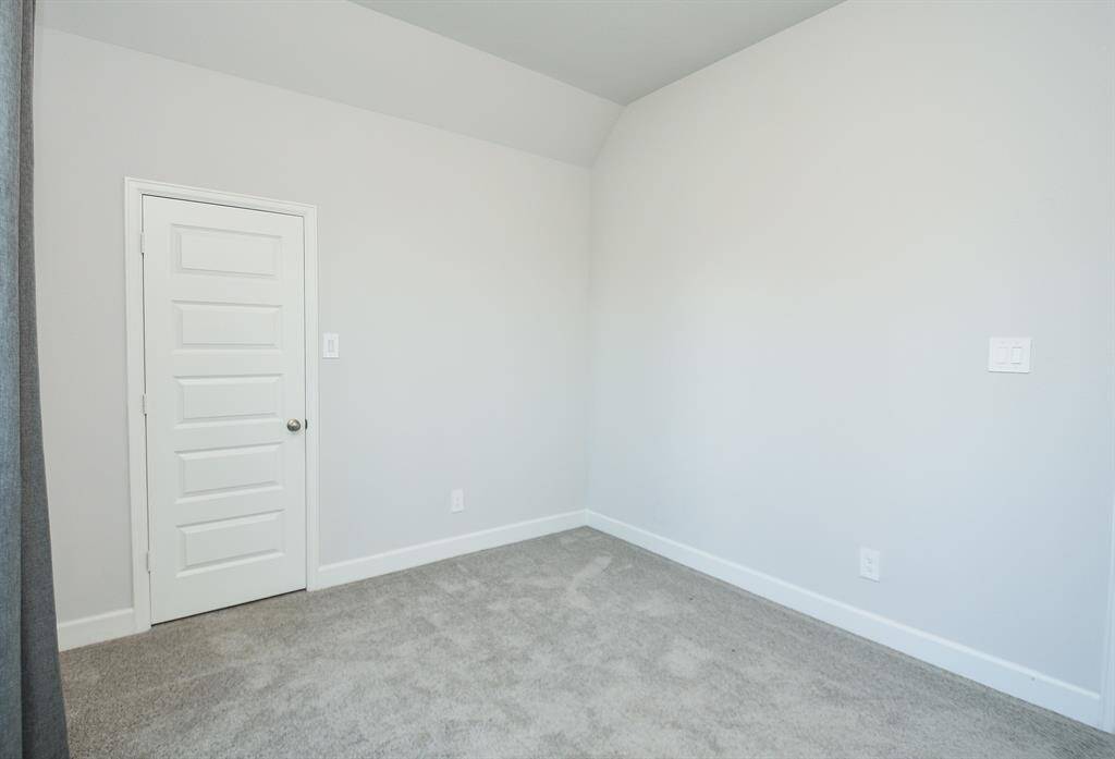 This room features soft gray walls, plush carpeting, and a white door, offering a clean and neutral space that’s ready for personalization.