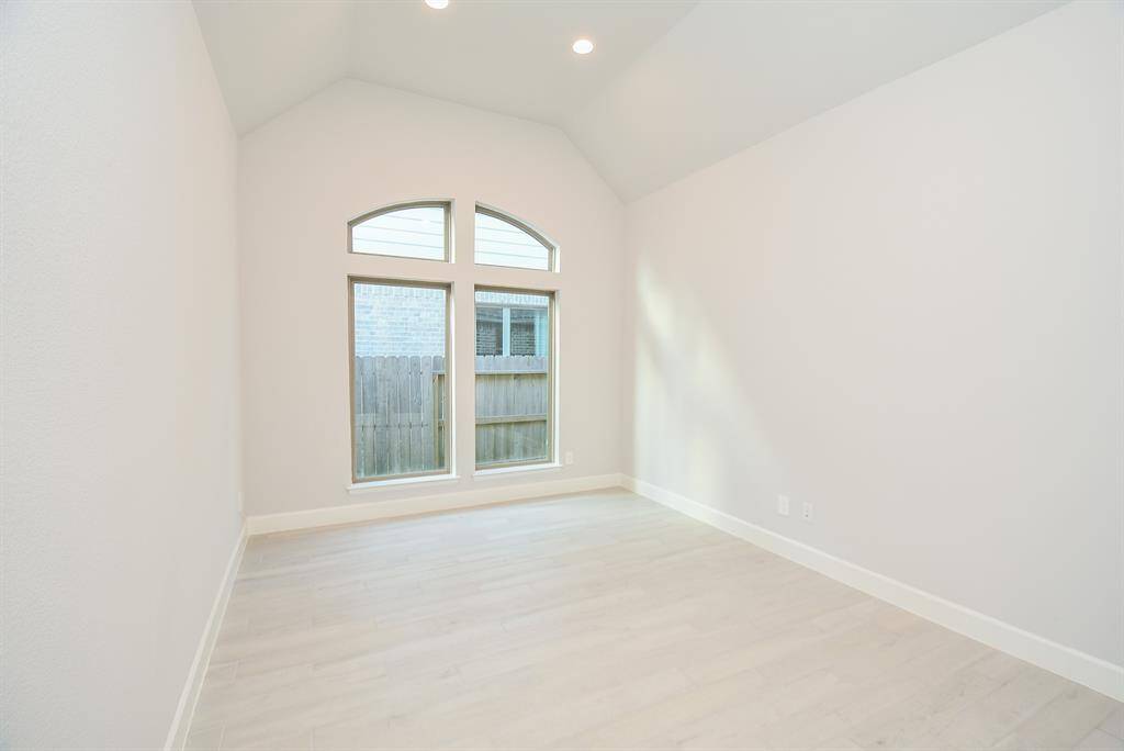 Bright, spacious room with high ceilings and large arched windows, featuring light flooring and neutral walls. Ideal for a bedroom, dining room, or office space.
