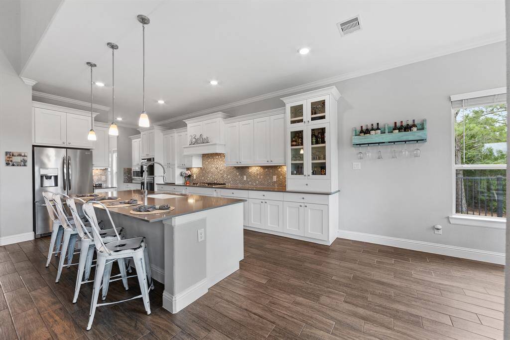 The kitchen features grey glazed white cabinets with a light brown hexagonal tile backsplash, offering a modern, textured look.