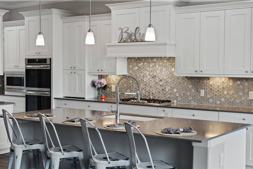 Above the kitchen island, three elegant light fixtures provide both style and illumination, highlighting the heart of the kitchen.