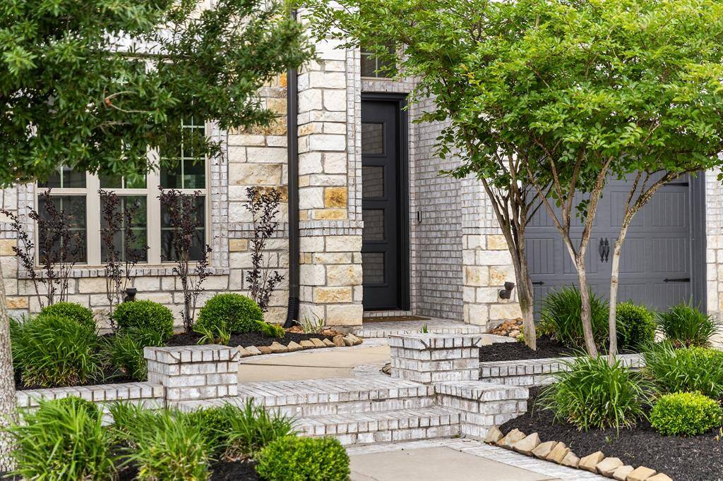 The house has a grand covered porch with detailed stonework and beautiful elegant columns. The rich, wood-stained front door with glass inserts offers a warm and luxurious entry to a place you would love to call home.