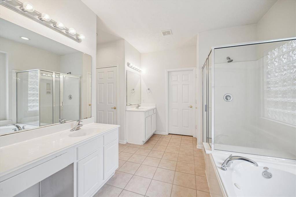 This primary bathroom features a spacious double vanity, ideal for sharing while maintaining your own side, plus a separate shower and jacuzzi for added comfort.