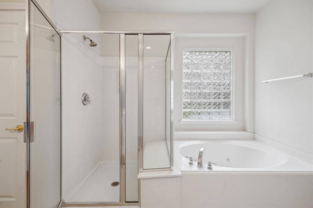 This bright, inviting primary suite features a Jacuzzi tub, perfect for unwinding in complete privacy and comfort.