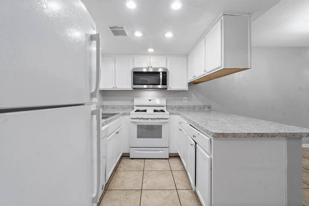 Galley kitchen with gas stove and refrigerator.