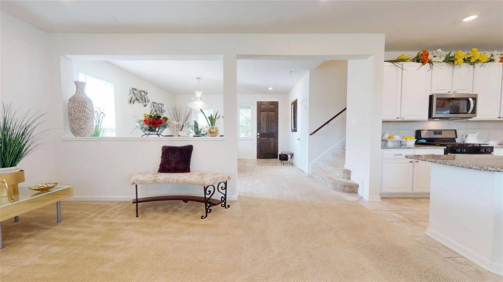 What a great view from the living room to the dining area on the left, front door ahead, wide staircase, and kitchen on the right.