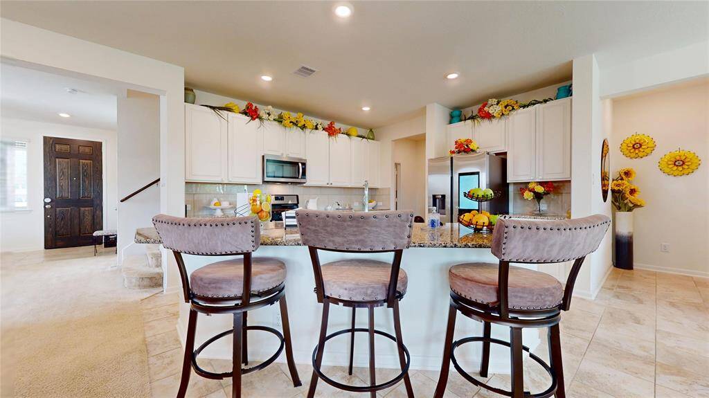 This chef's kitchen has a cooking gas range, microwave, plenty of storage cabinetry up and down, tile backsplash, large granite countertop, and stainless-steel appliances. The refrigerator does not stay.