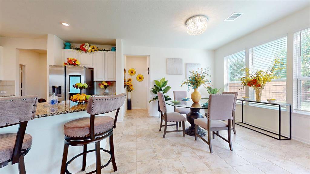 In the breakfast room to the right, the abundant windows let in natural light, creating a beautiful ambiance for a meal together. The half-bath ahead, and kitchen view on the left.