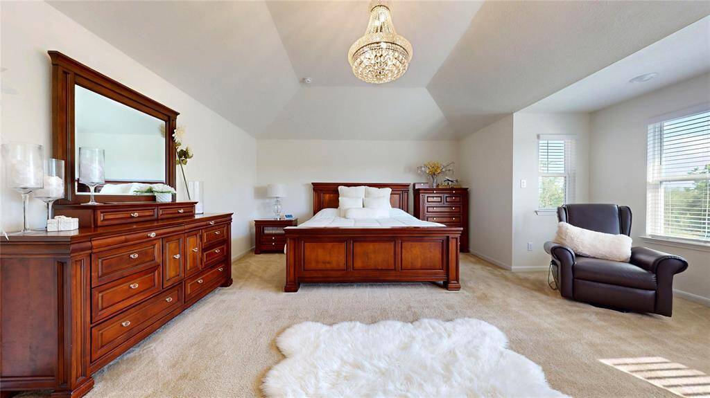 This spacious primary bedroom with vaulted ceiling, and a stylish chandelier adds a touch of luxury.
