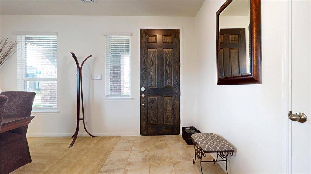 Welcoming view of the main entrance from the inside. The entryway has a dark wood front door. Lots of natural light pours in through the windows, making the space bright and inviting, perfect for greeting guests.