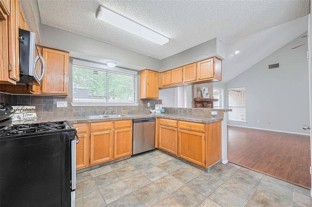 Gas range, stainless appliances and a view to the backyard and living space add to the joy of meal-prep.