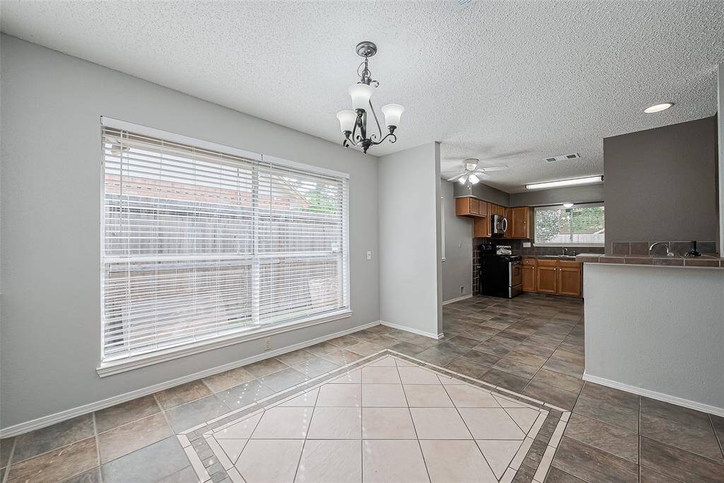 This elegant dining room features inlaid tile flooring, a chandelier, large window and chair rail along the back wall.