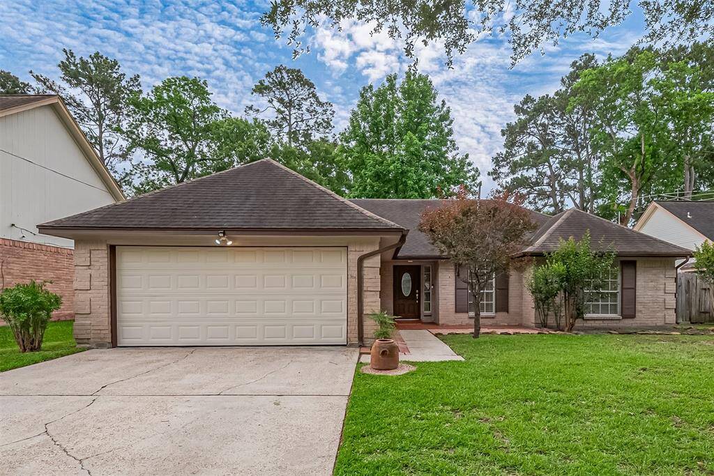 Charming single-story brick home featuring attached two-car garage and oversized driveway.