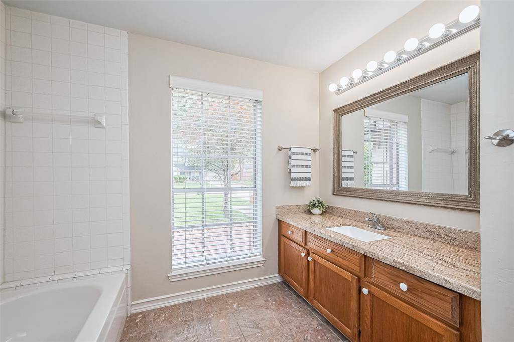 Bathroom 2: granite countertop, undermount sink, framed mirror, wooden cabinets & natural light.