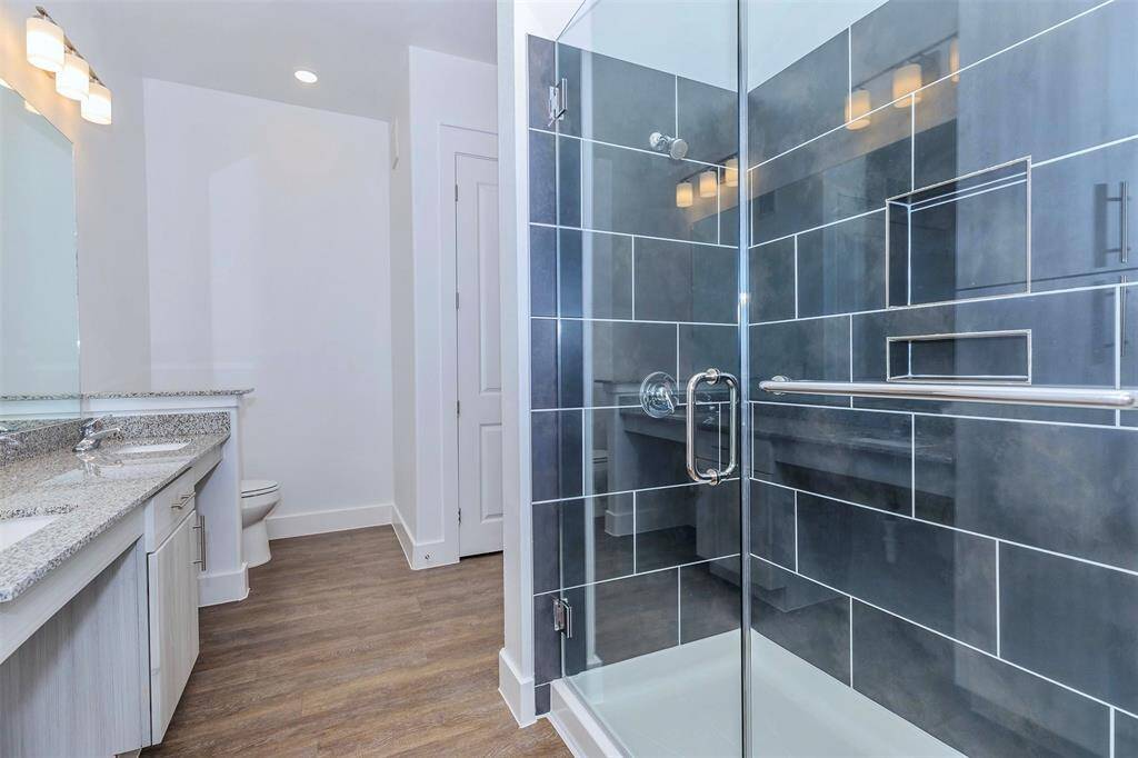 Bathroom with double sinks, granite countertops, and walk in closet