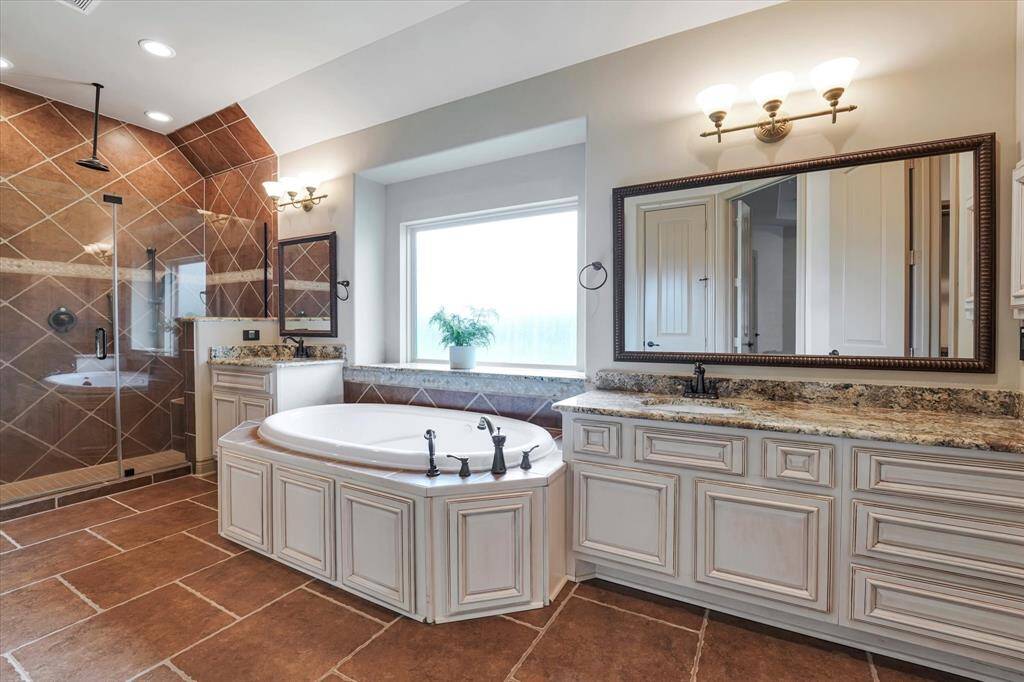 Indulge in a Hollywood-style bathroom with elegant tile work, a spacious walk-in shower, dual sinks, and a luxurious soaking tub. Plus, enjoy abundant closet space.