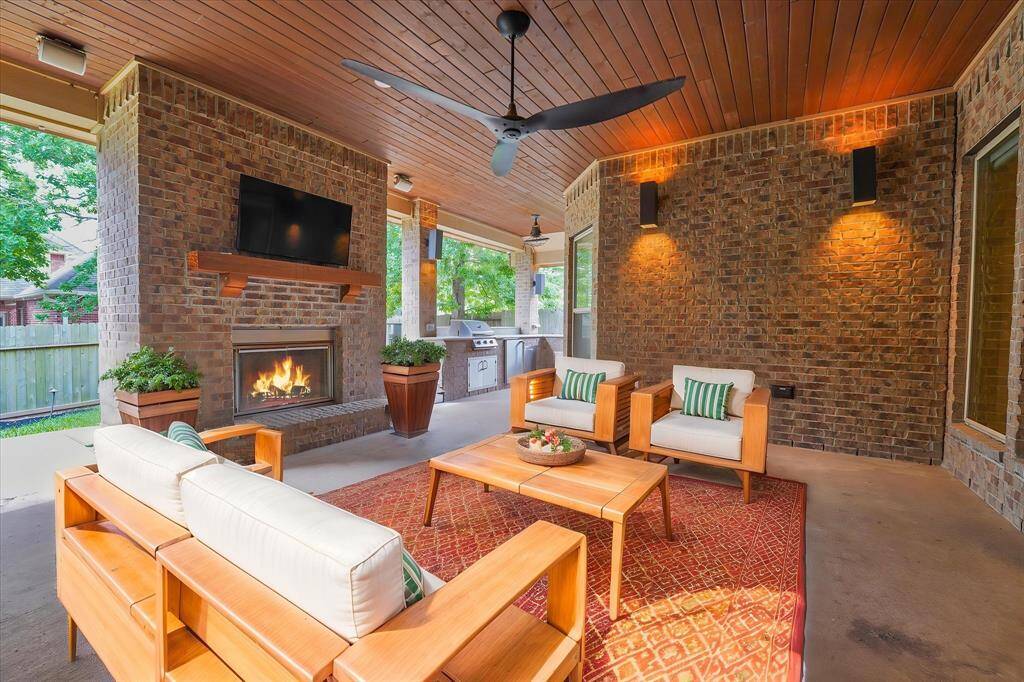 Experience outdoor luxury with this spacious covered patio, featuring elegant accent lighting, a cozy fireplace, and a fully equipped kitchen—ideal for entertaining.
