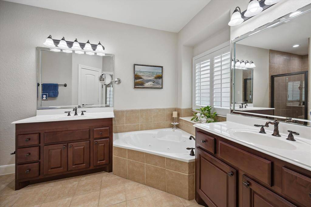 The primary bath includes separate vanities and a jetted tub with a window.