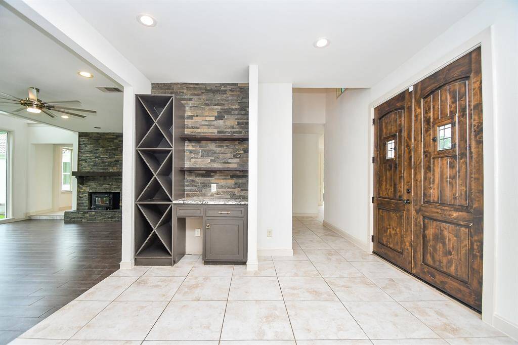 Entry hall leading to the sunken living area features wine storage area, stone backsplash and wood shelving