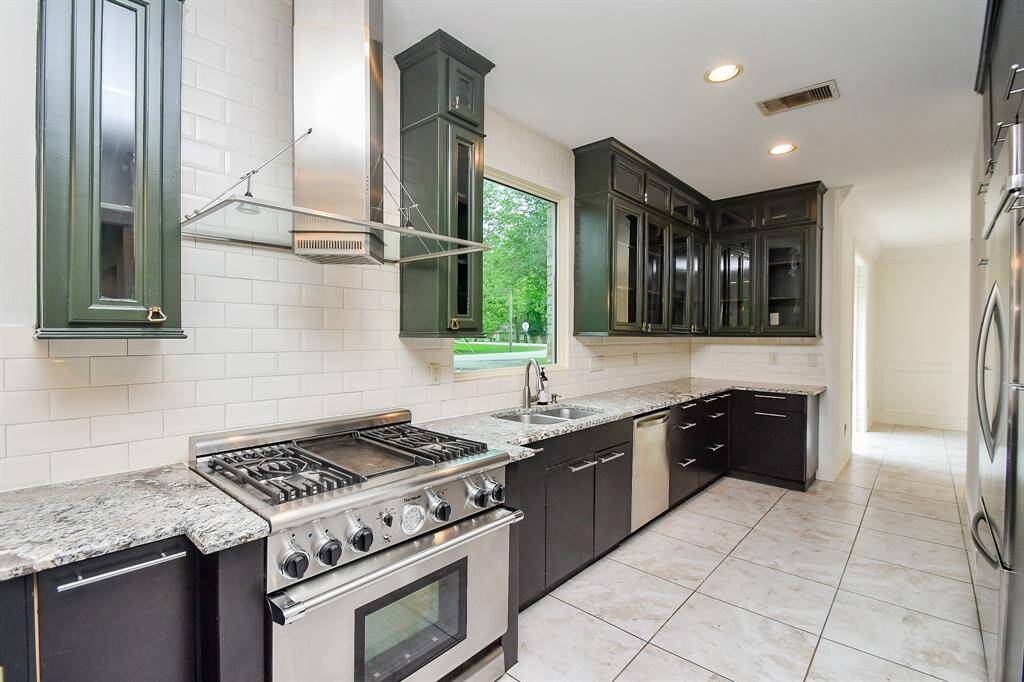Thermador gas stove, flat top burner, sleek ventilation hood with lighting and subway tile backsplash
