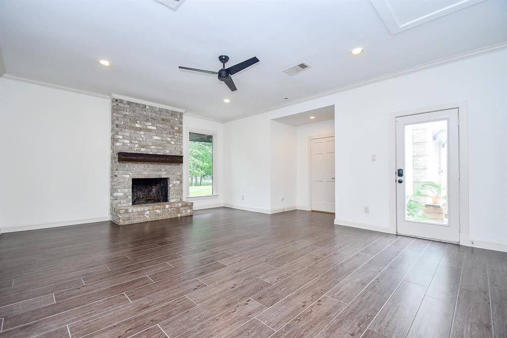 Enormous primary suite with wood grain tile, wood burning fireplace, floating mantle shelf and large windows